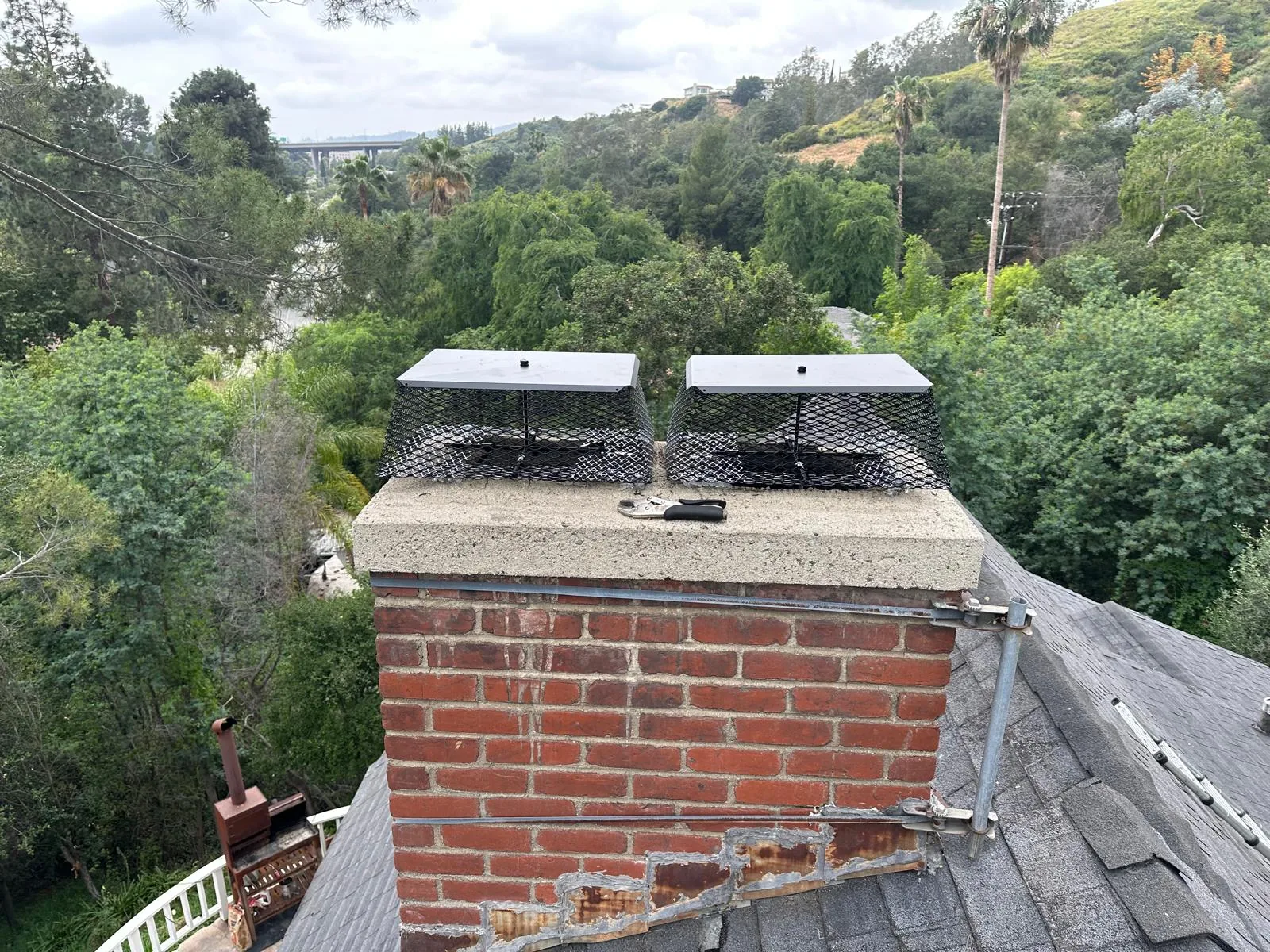 A repointed brick stack with two new caps above a hillside street