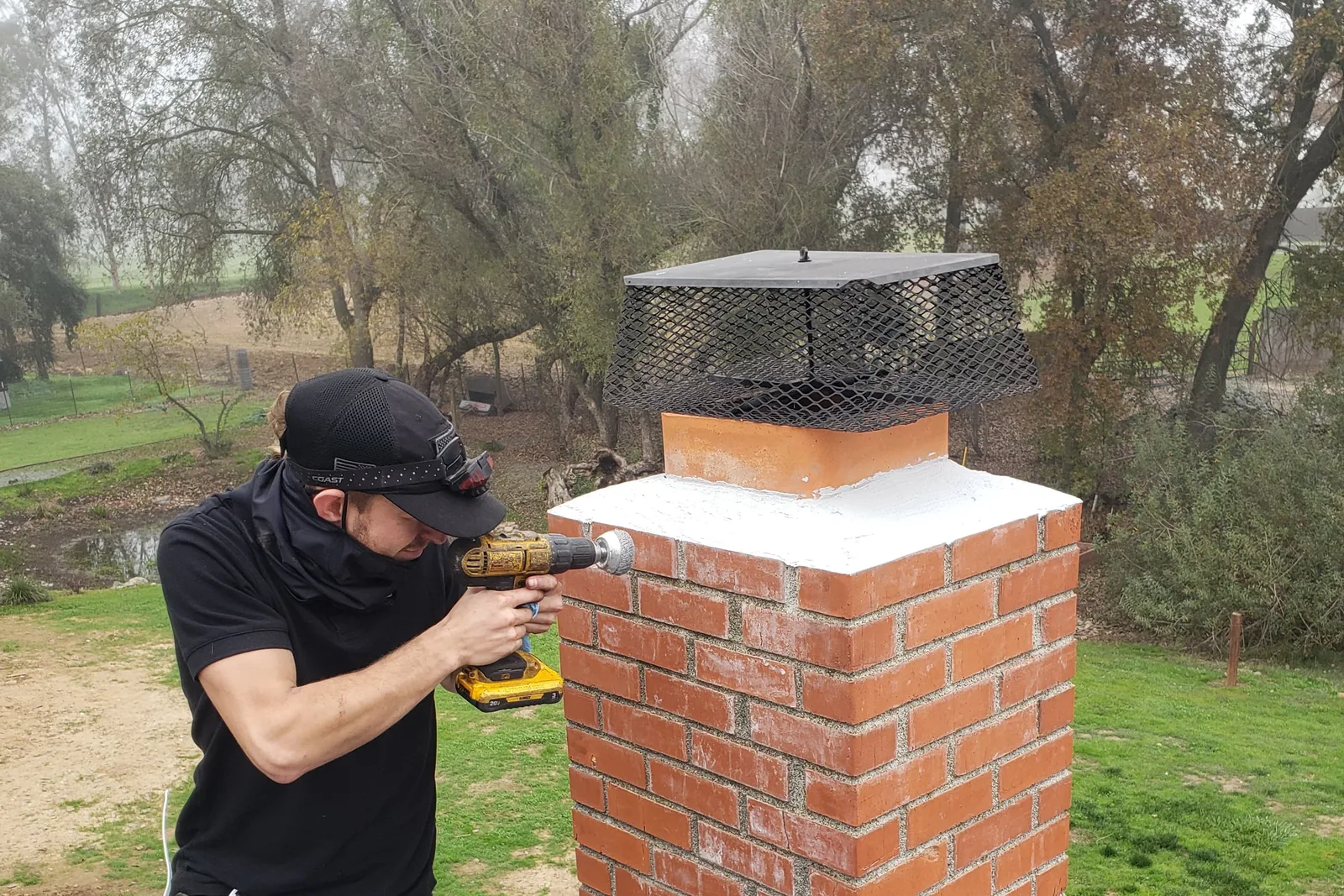 A Chimney Guys technician finishing a rebuilt crown and new cap on a brick chimney