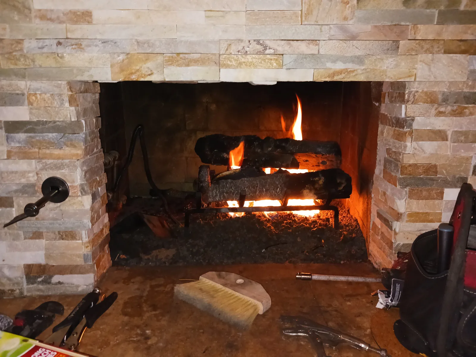 A serviced gas log set burning cleanly in a stone fireplace